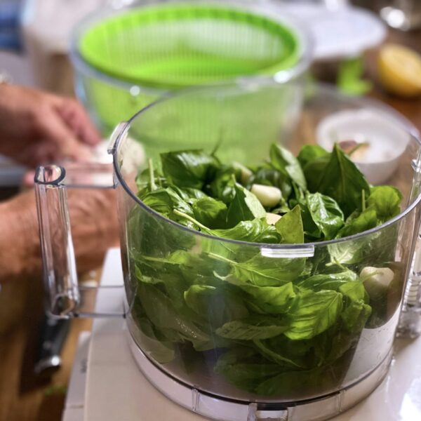 A jar of arugula walnut pesto next to a handful of arugula leaves