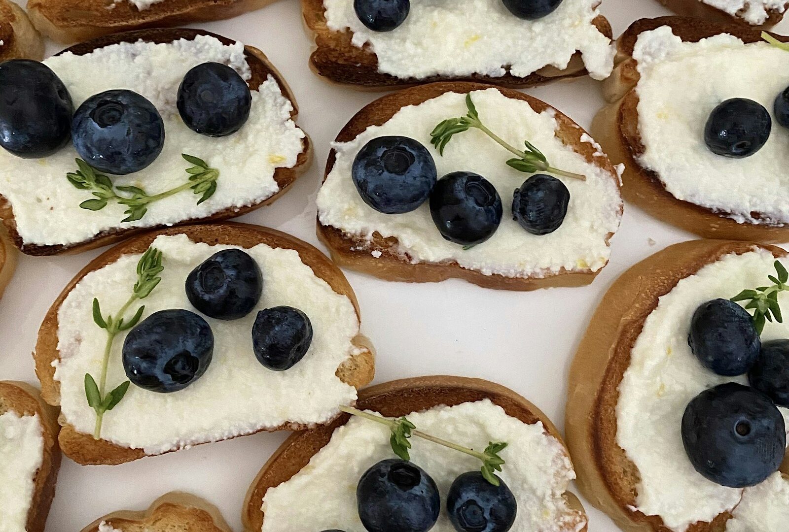 Slices of toasted bread topped with ricotta and a line of pesto