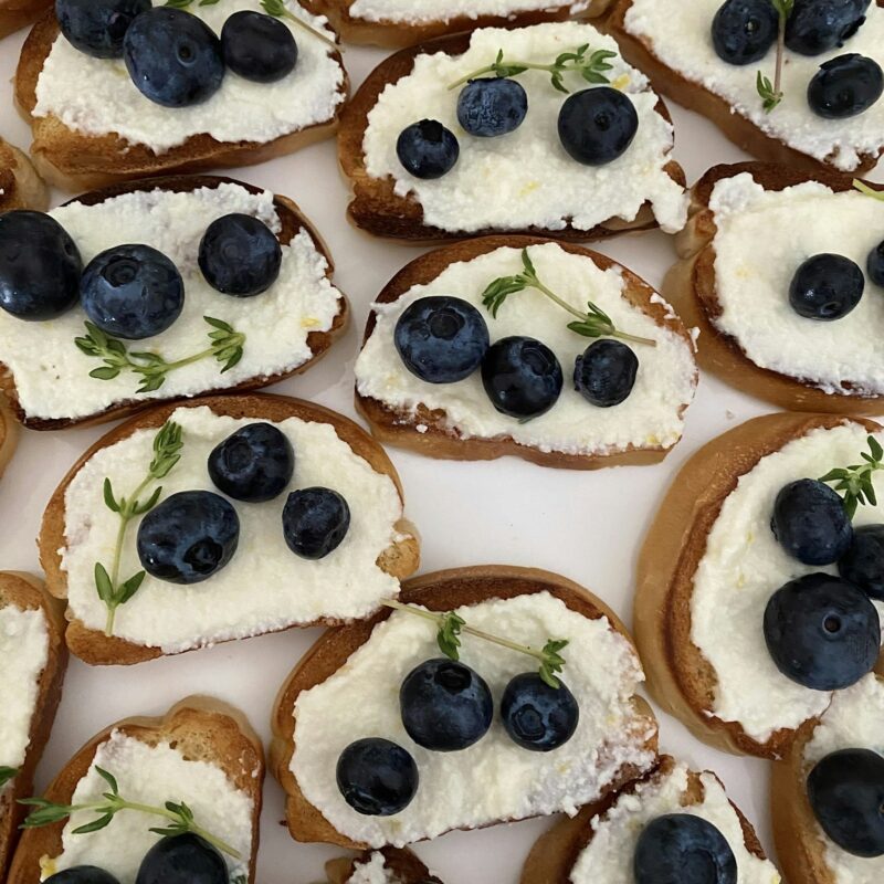 Slices of toasted bread topped with ricotta and a line of pesto