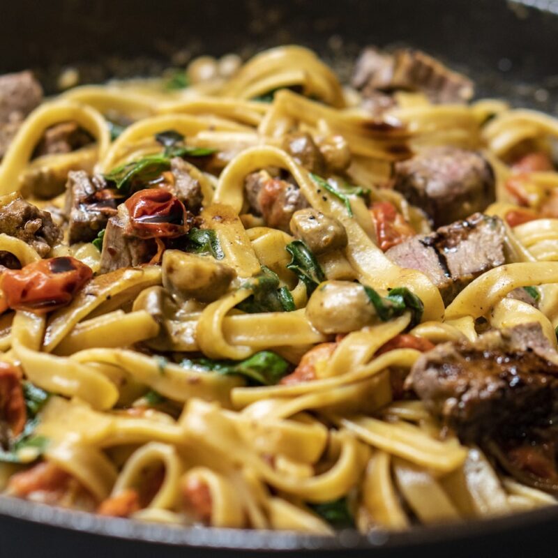 A plate of spaghetti tossed with bright green pesto, grated Parmigiano on top
